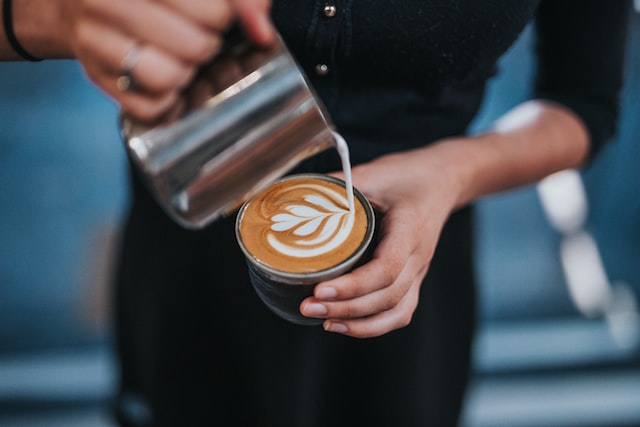 Mujer generando Latte Art con espuma de leche hecha con un espumador de leche eléctrico