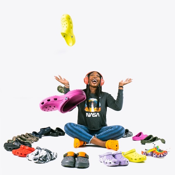 Mujer joven rodeada de Crocs Classic Crocs